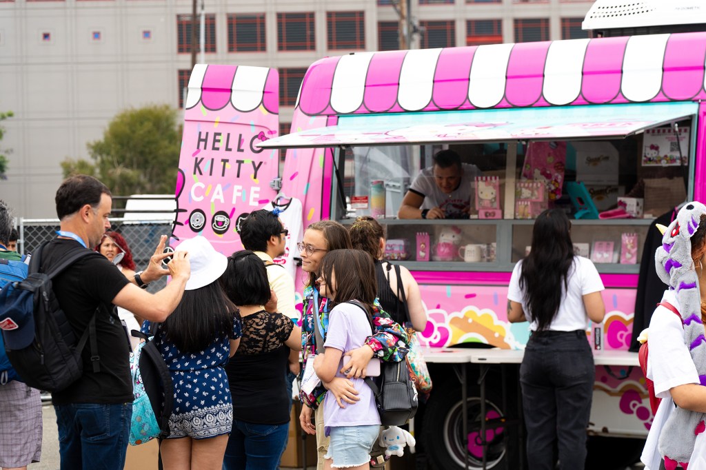 a pink cafe truck with a crowd of people around it