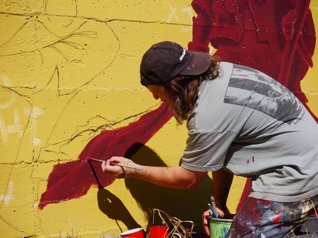 A man paints a wall with red paint