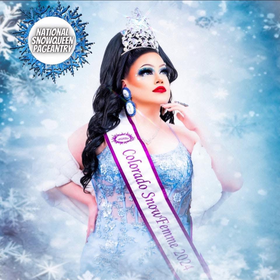 A drag queen in a blue dress and sash