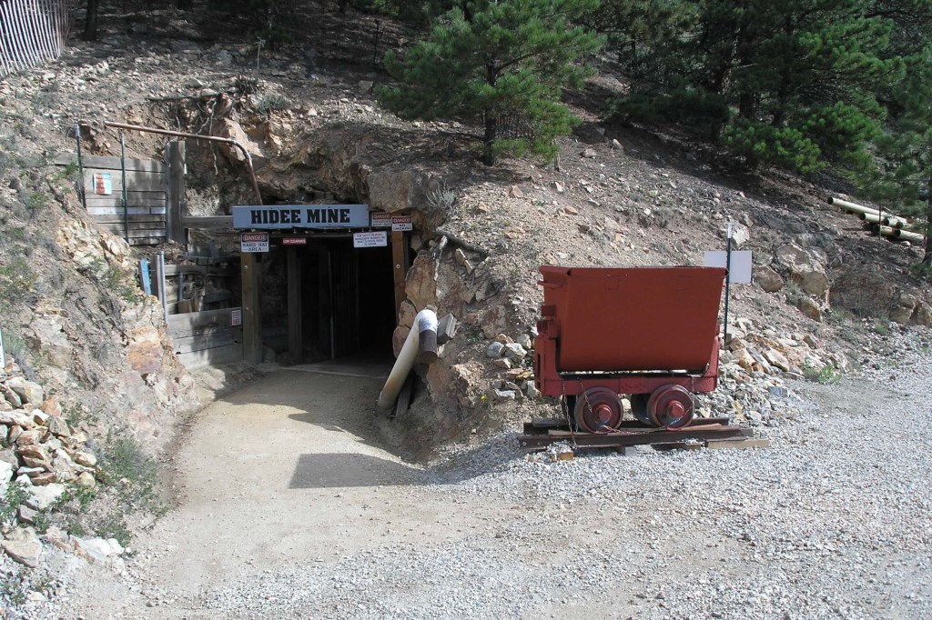 A vintage mine cart stationed outside the portal of Hidee Gold Mine