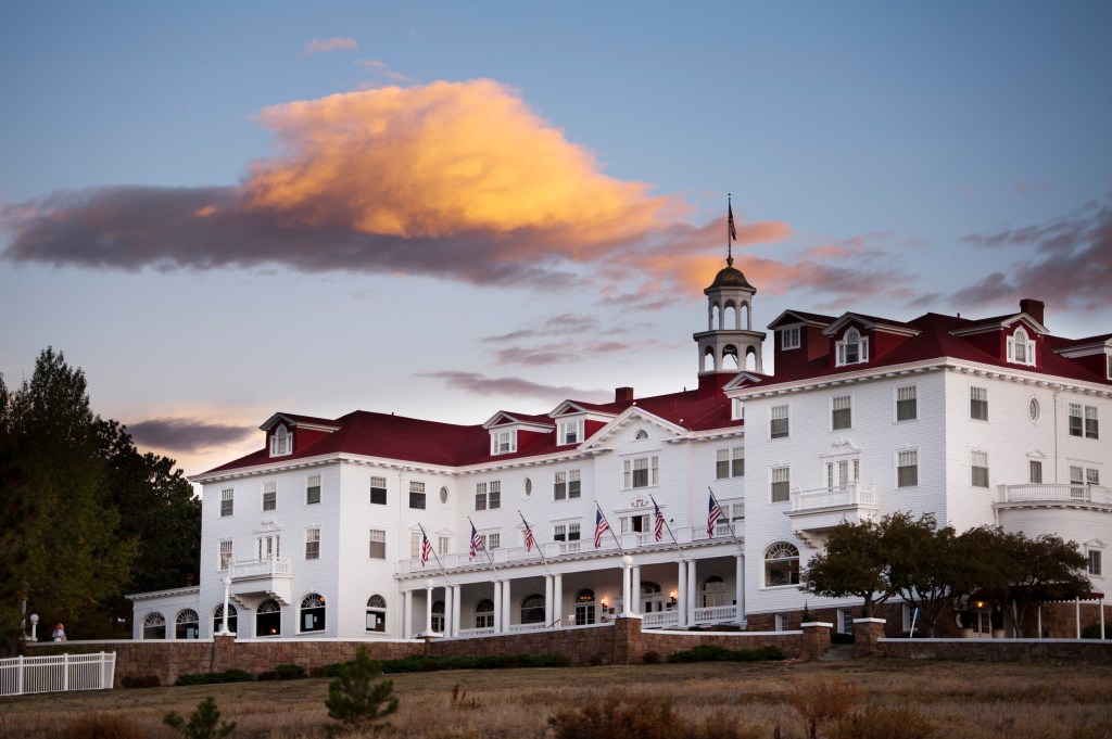 An exterior shot of the Stanley Hotel, featuring a red roof and white siding