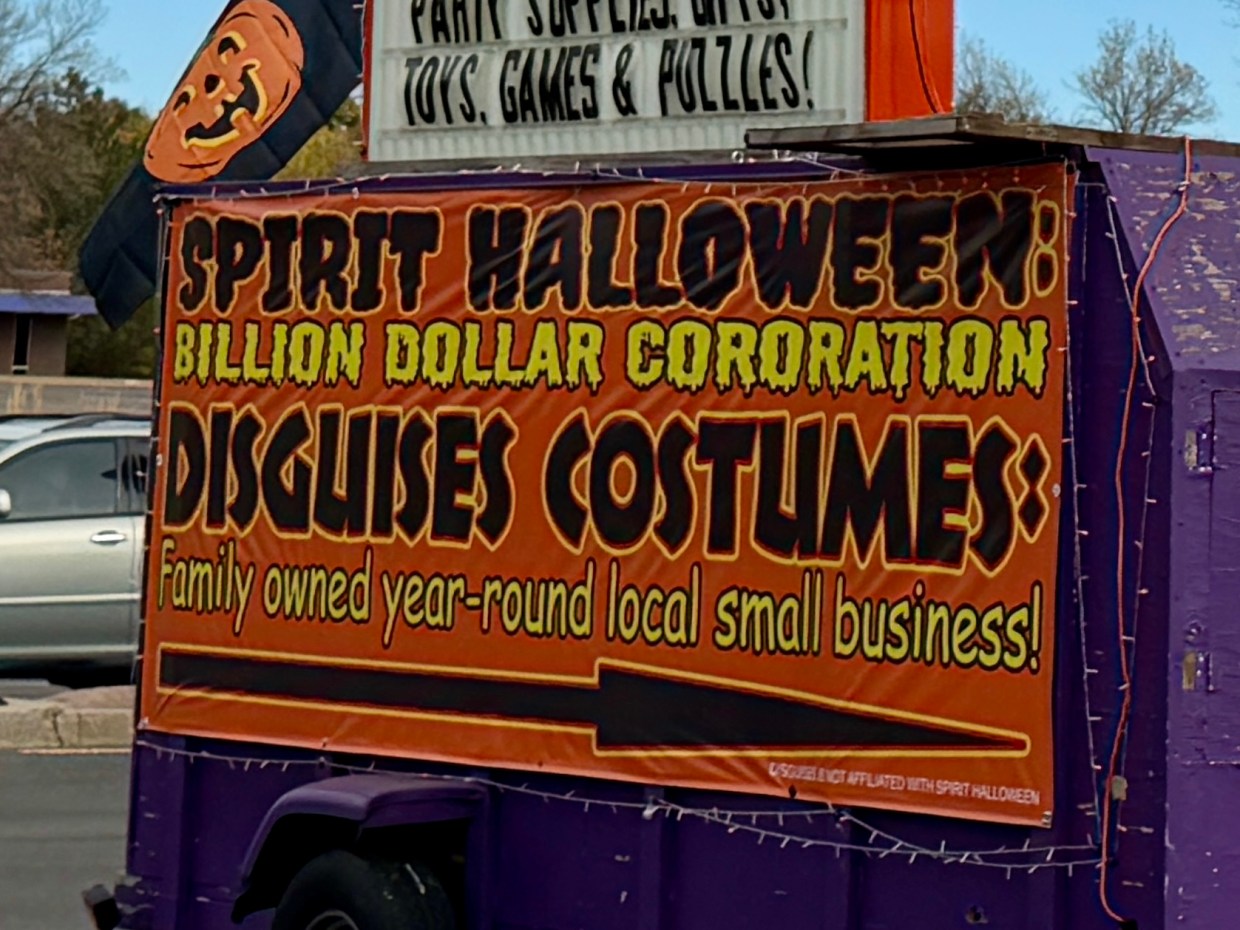 The sign at Disguises decries Spirit Halloween as a billion-dollar corporation