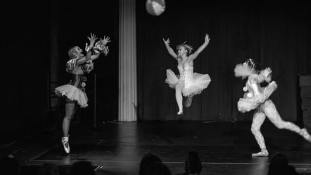 Clowns pass a beach ball to each other.