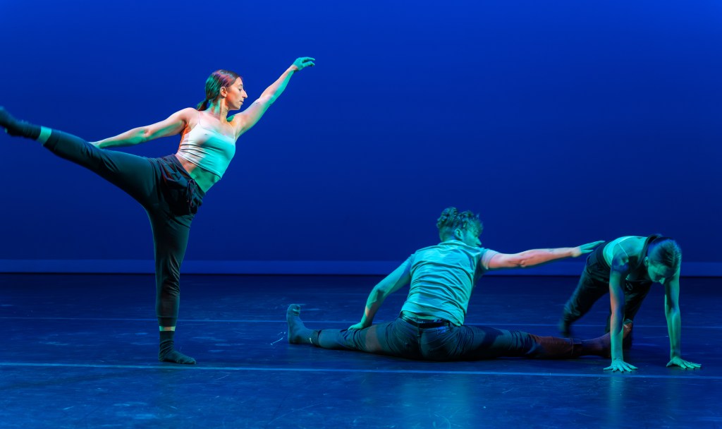 People dance onstage in blue light.