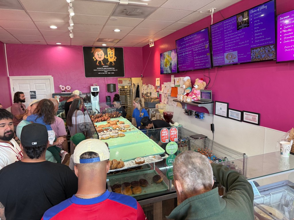 a line of customers at a donut shop