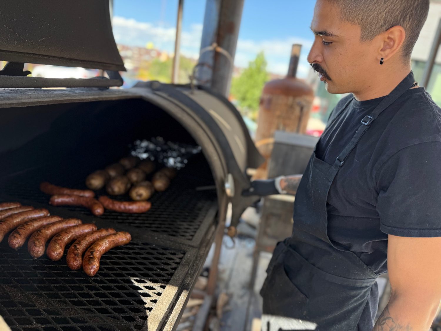 a bbq smoker and man working it