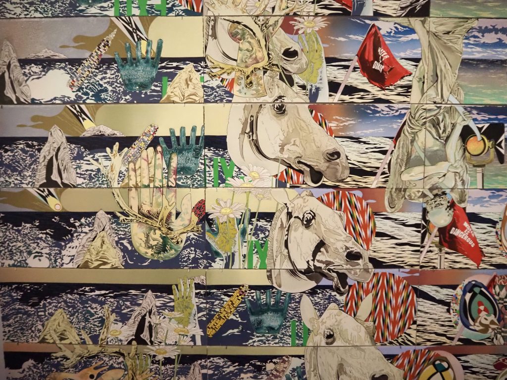 A colorful artwork featuring hands, corn, water and horses, among other things