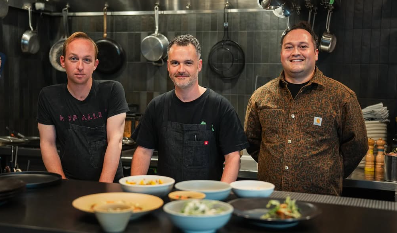 three people posing behind a counter