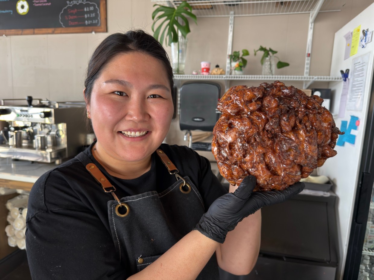 a woman holding an apple fritter