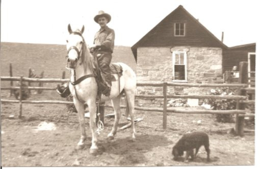 black and white photo of man on his horse in front of ranch