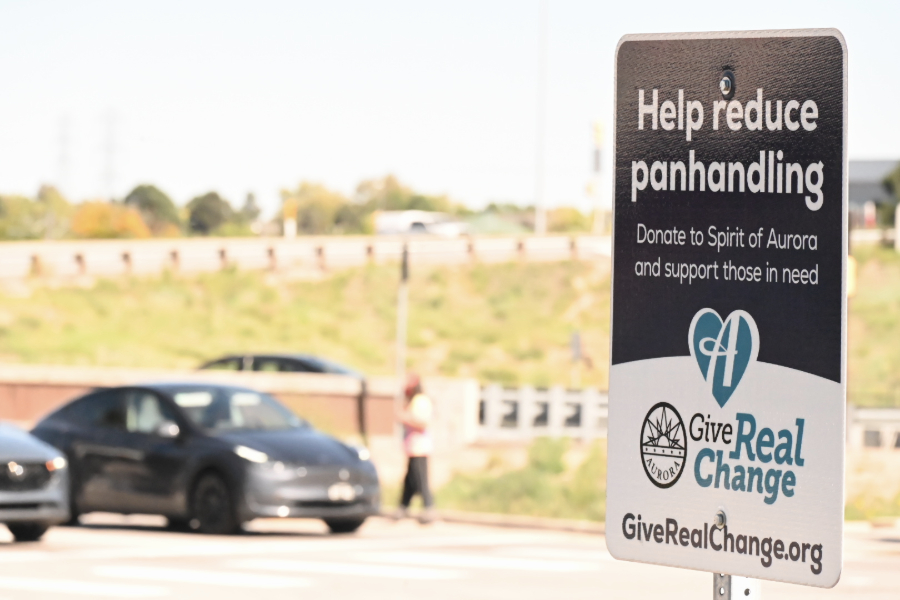A panhandling sign in Aurora with a panhandler in the background.