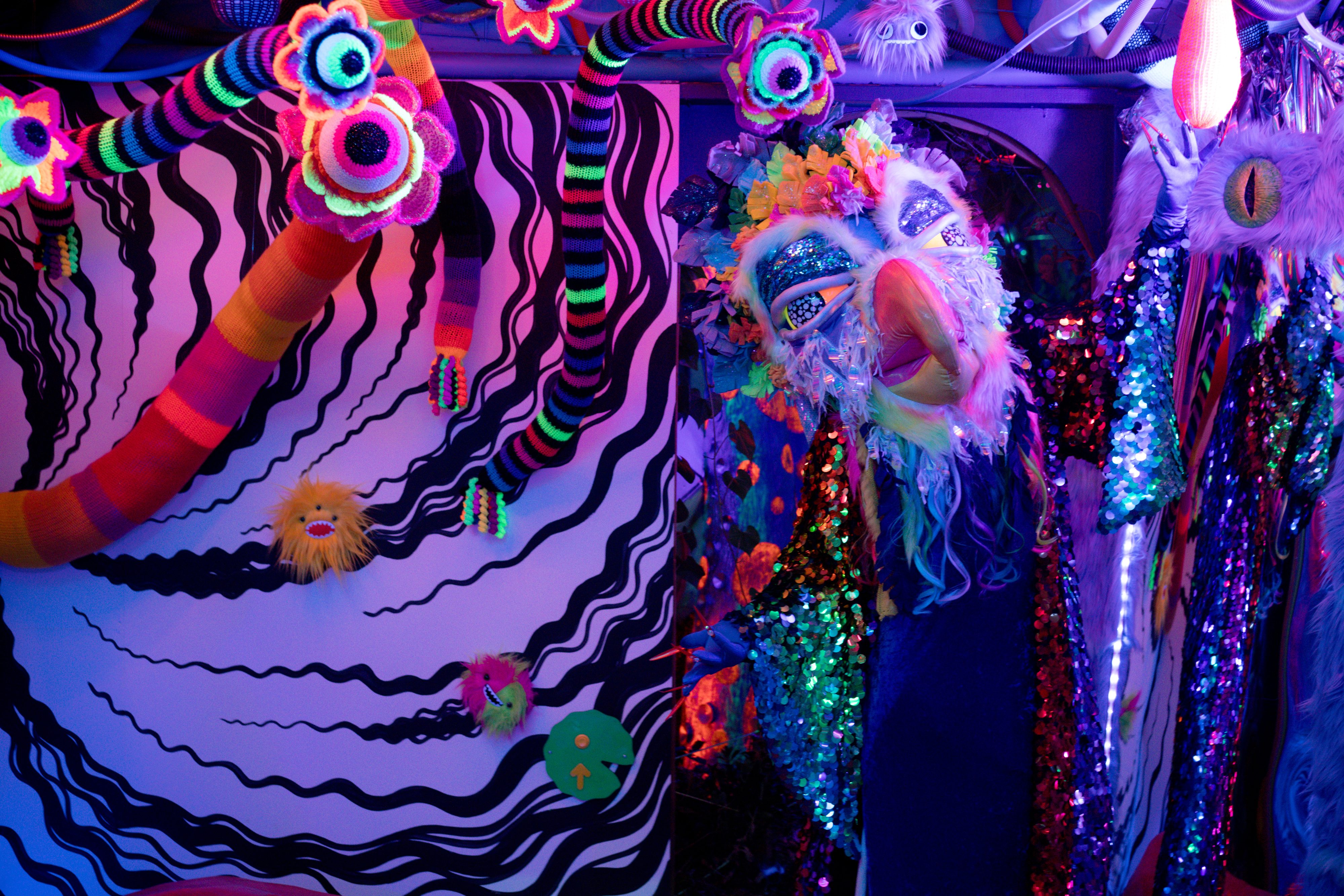 A masked performer in a colorful immersive space.