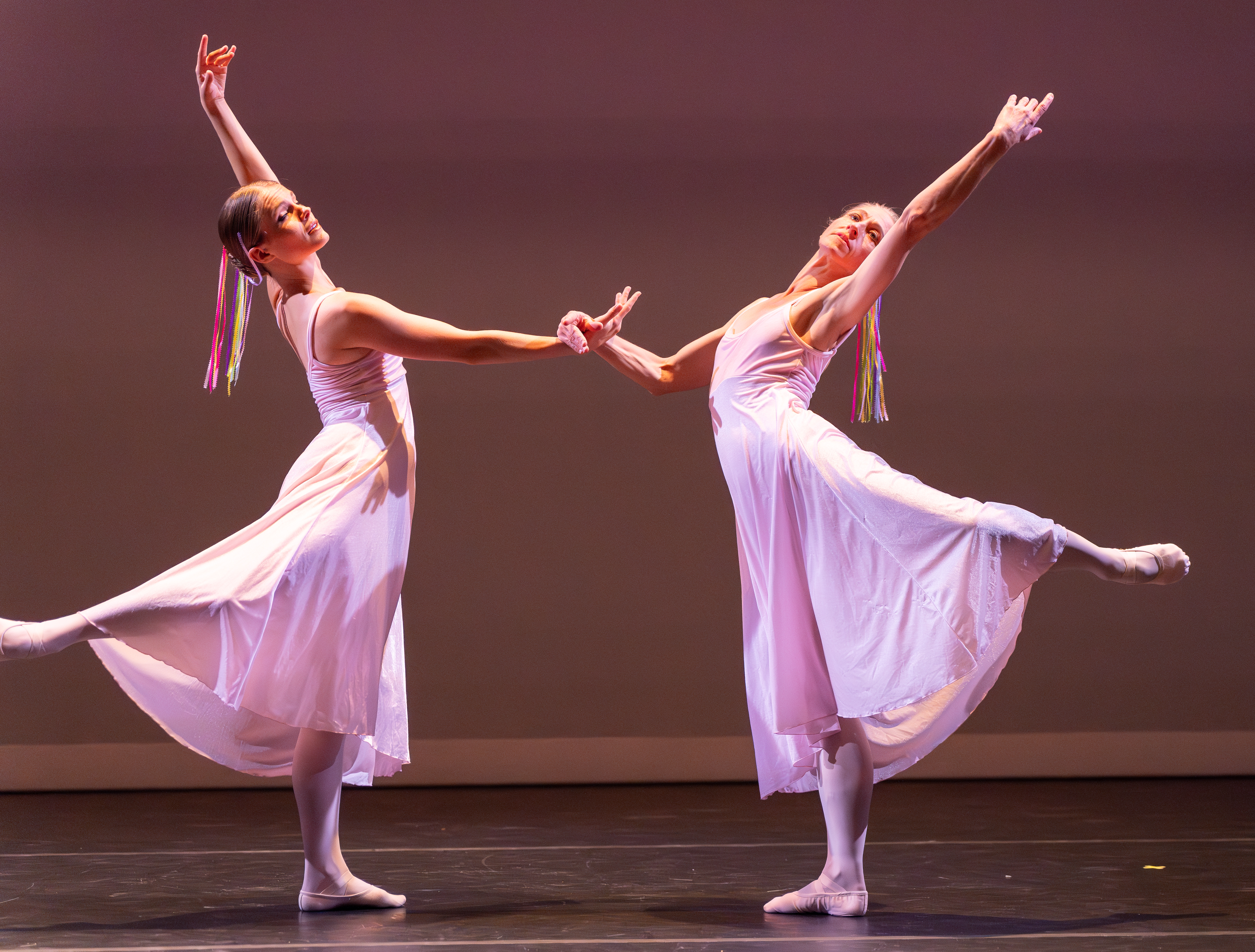 Two ballerias strike a dramatic pose with their hands and legs up.