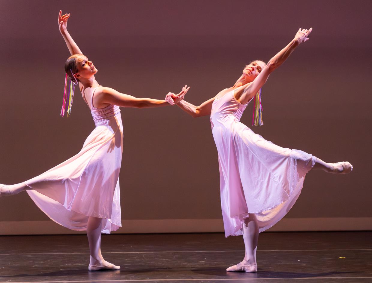Two ballerias strike a dramatic pose with their hands and legs up.