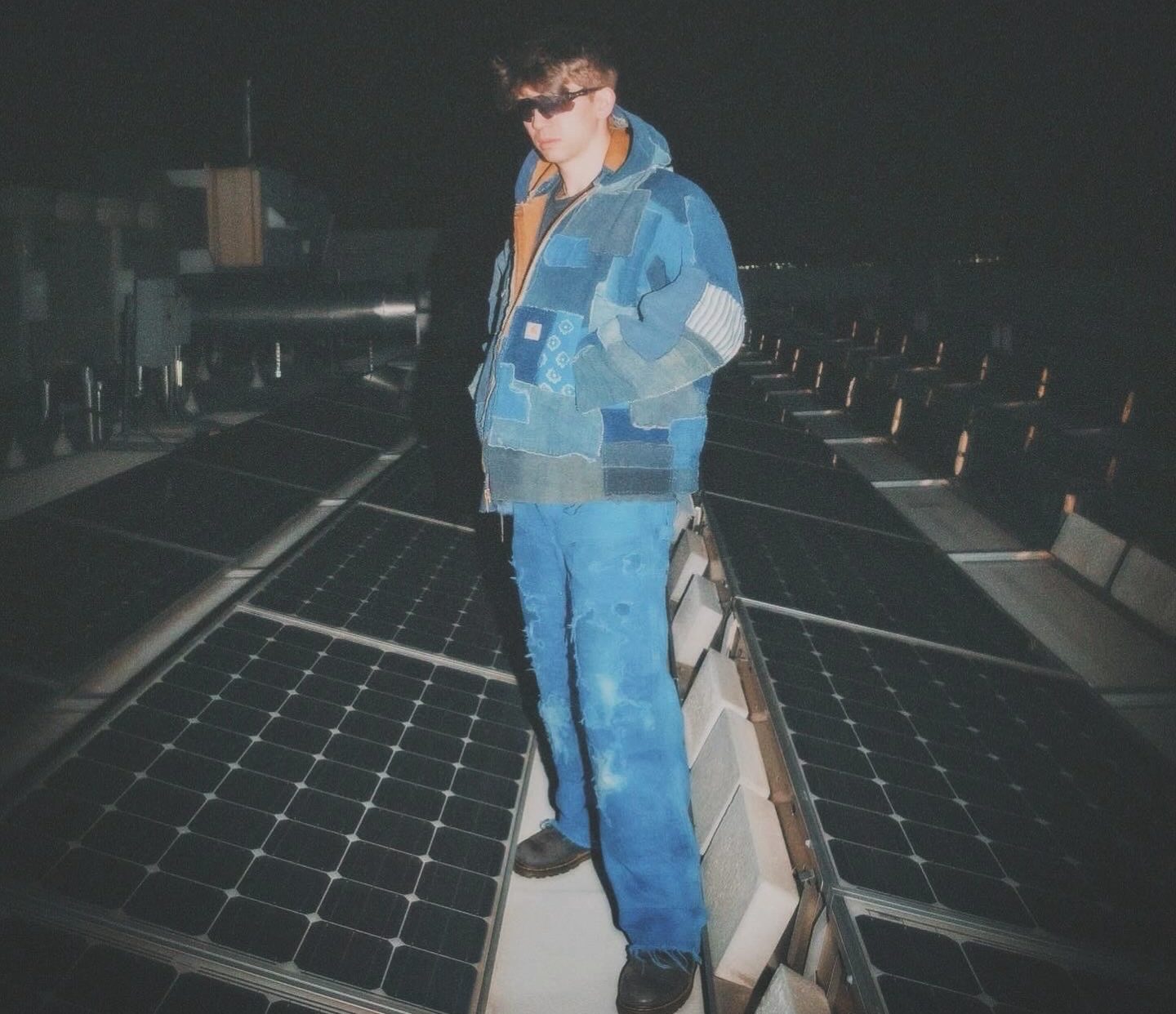 Joshua Ryuju posing in his handmade patchwork denim jacket and jeans.