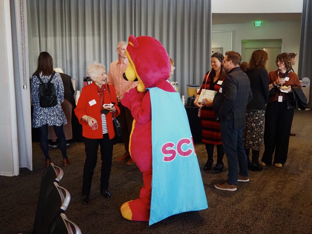 A woman greets a magenta bear mascot