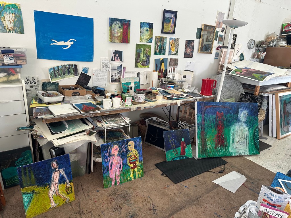 A cluttered art studio with painting everywhere.