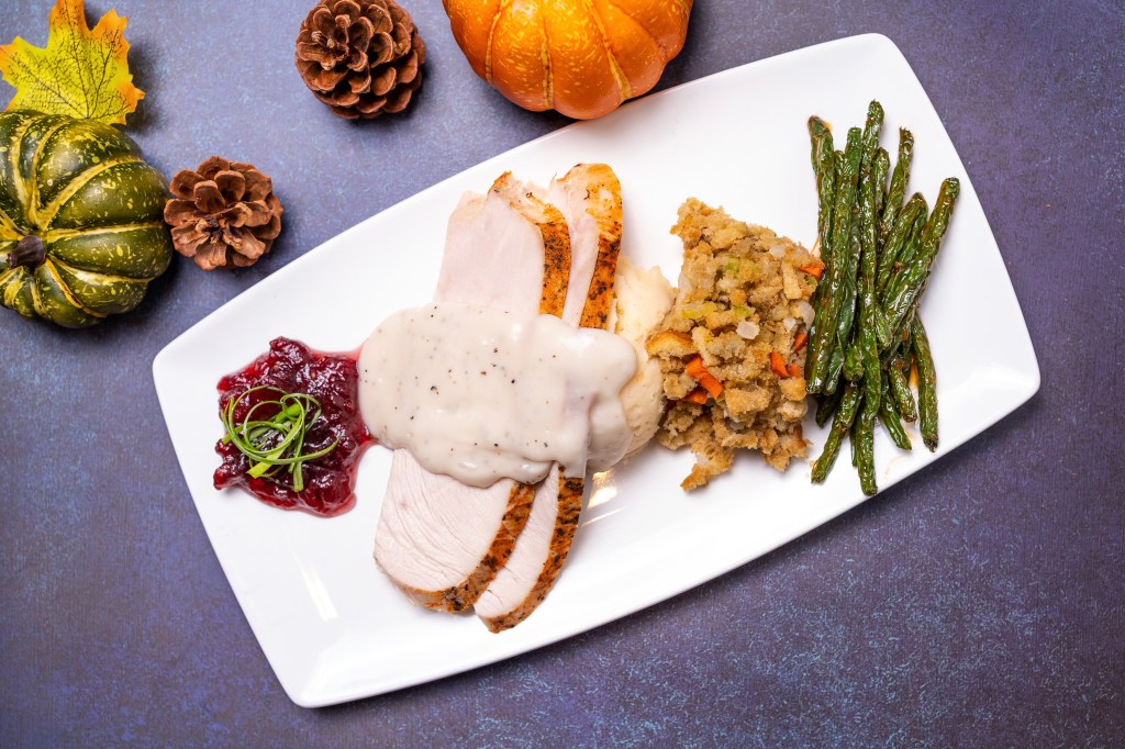 A plate of sliced turkey with gravy, green beans, stuffing and cranberry sauce from Kona Grill