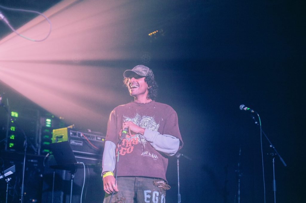 man laughing on stage holding a mic