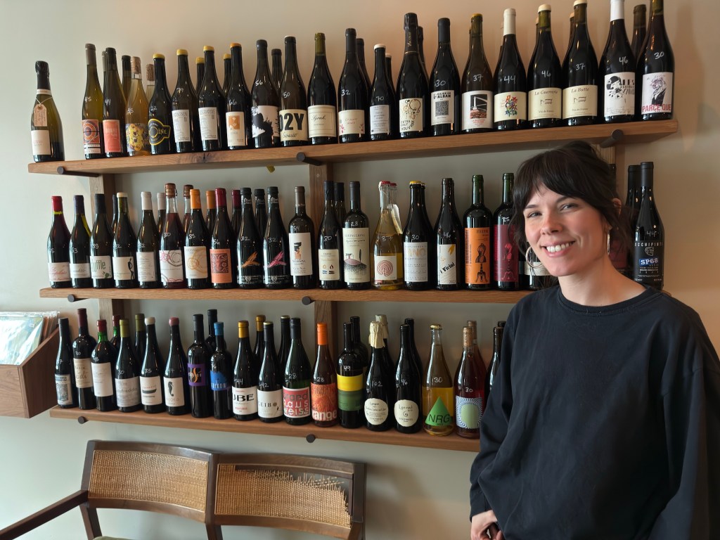woman standing in front of shelves of wine