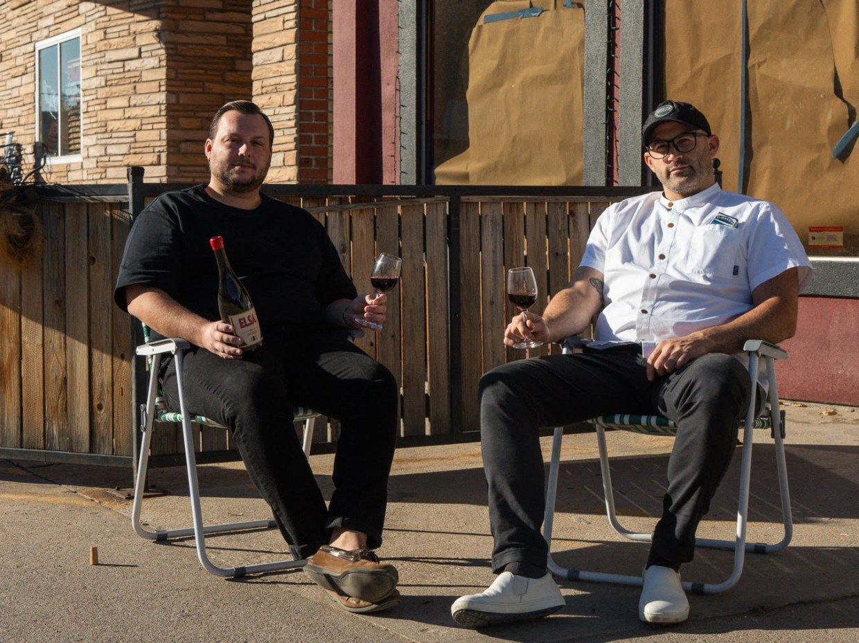 two men sitting in chairs holding wine glasses