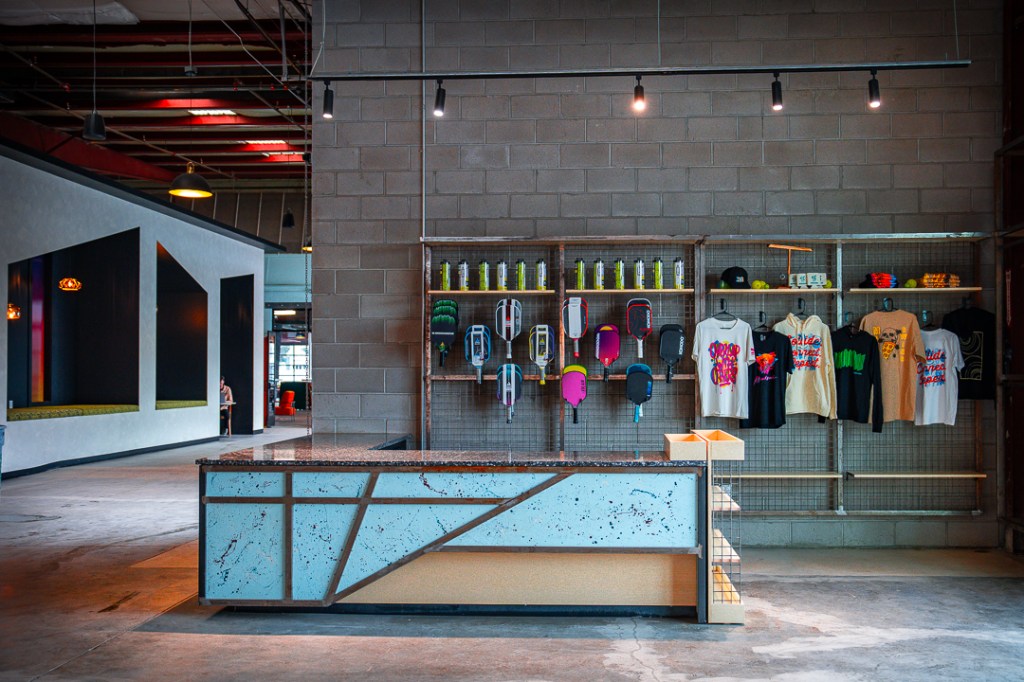 Retail wall and counter with paddles, shirts, balls, water bottles, and hats