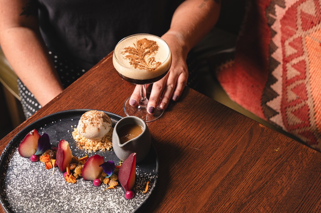 Red wine-poached pears on a black dish alongside an espresso martini from Toro