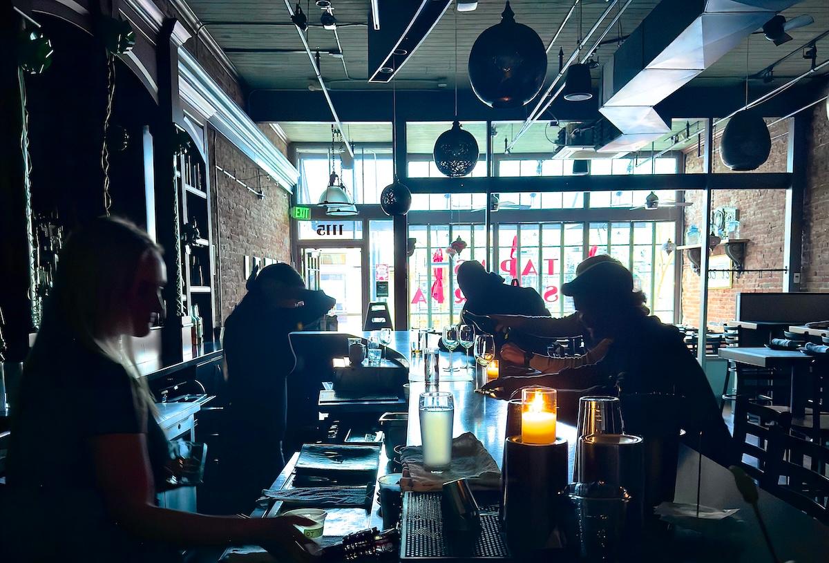 bartenders pour drink in dark bar without electricity