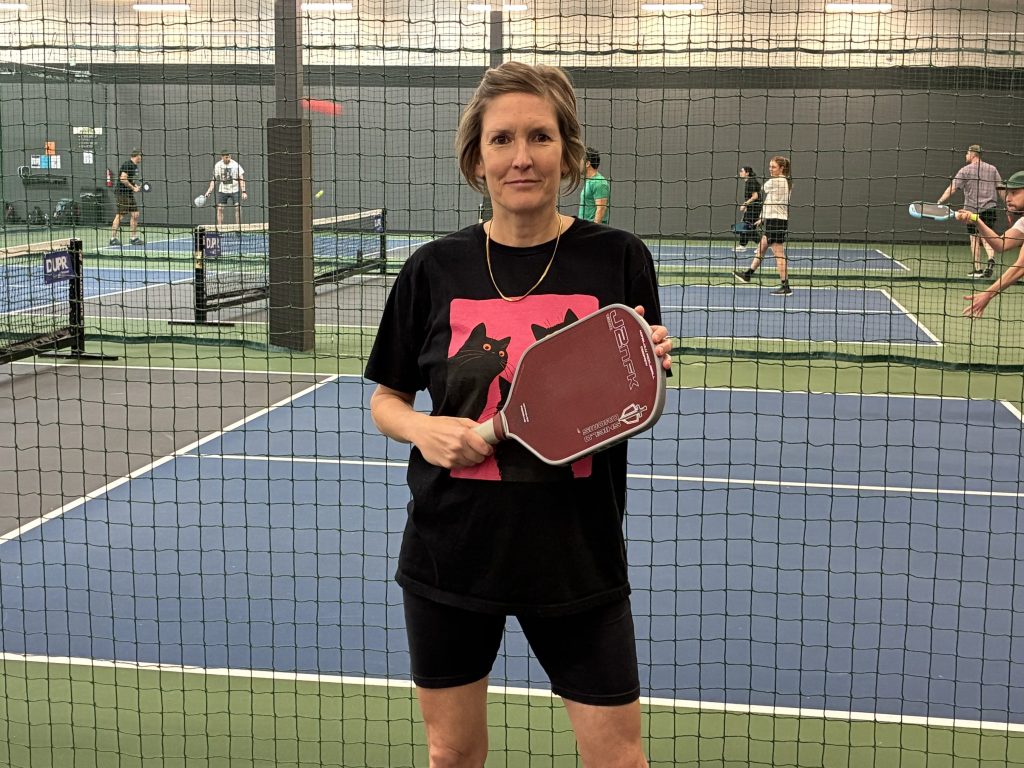 Woman poses near a pickleball court