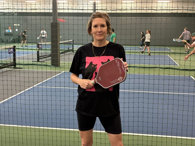Woman poses near a pickleball court