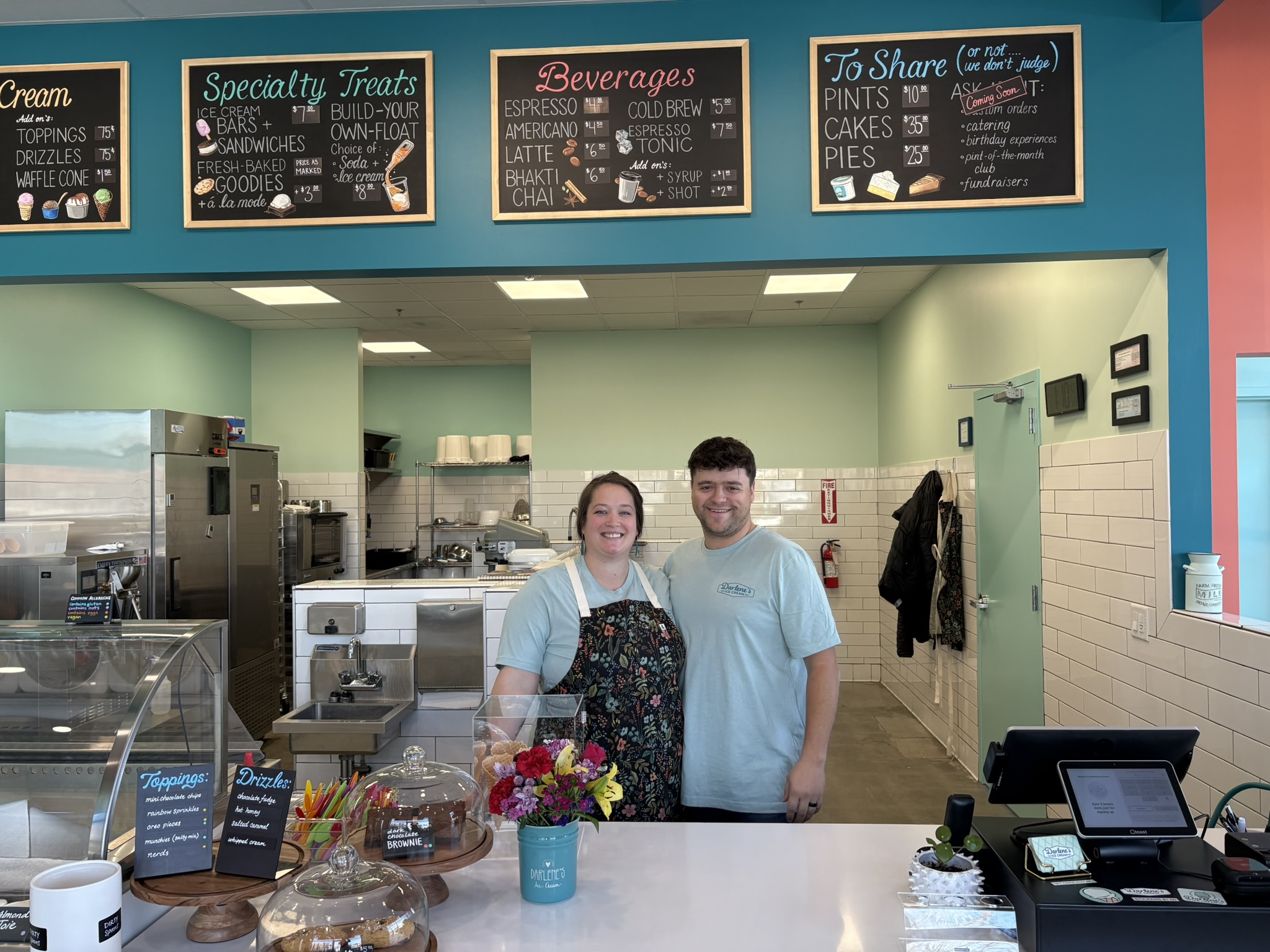 man and woman standing behind ice cream shop counter