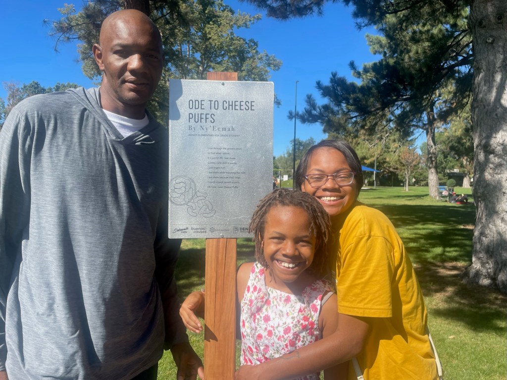 Three people gather around a sign