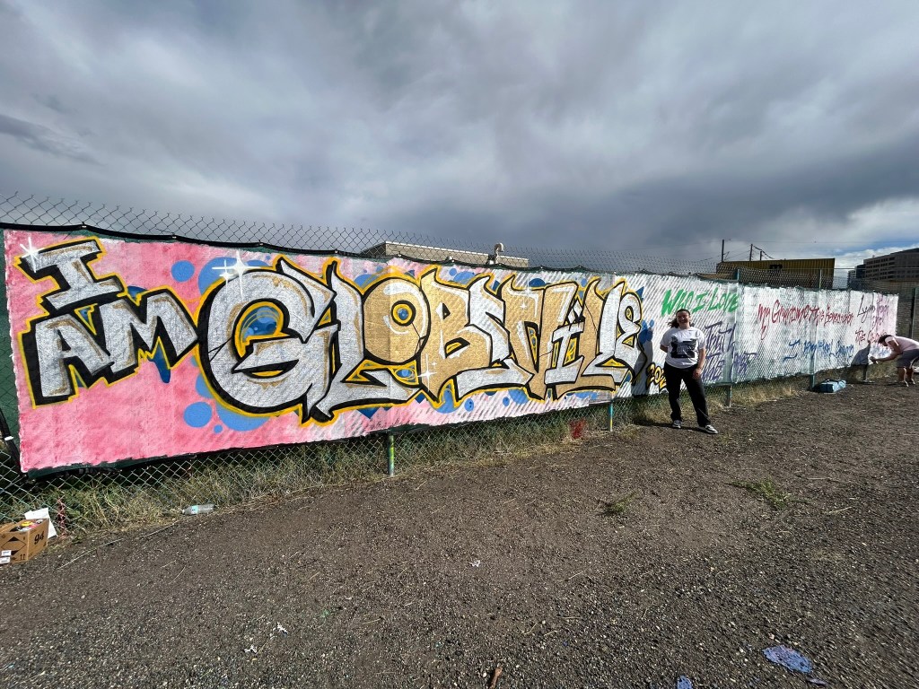 Women stands next to a graffiti-covered wall