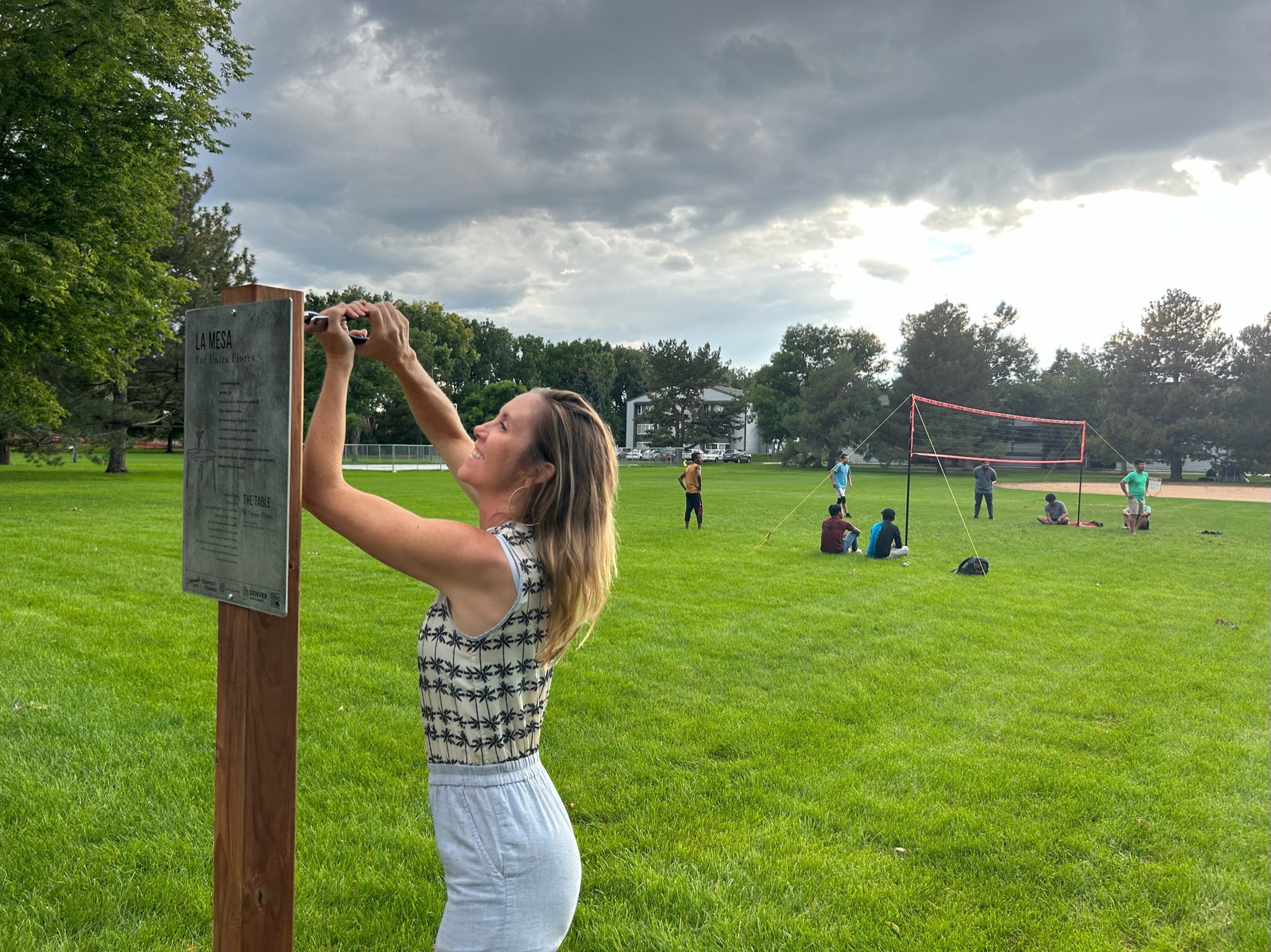 A woman installs a sign in a park