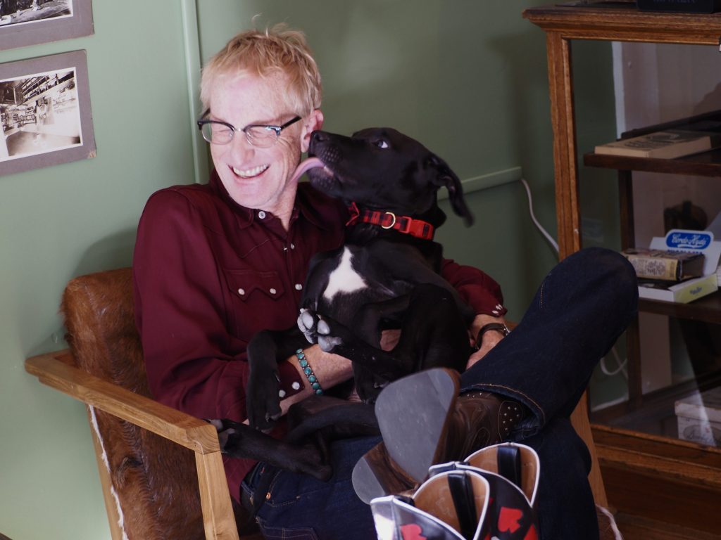 A man is licked by a black dog