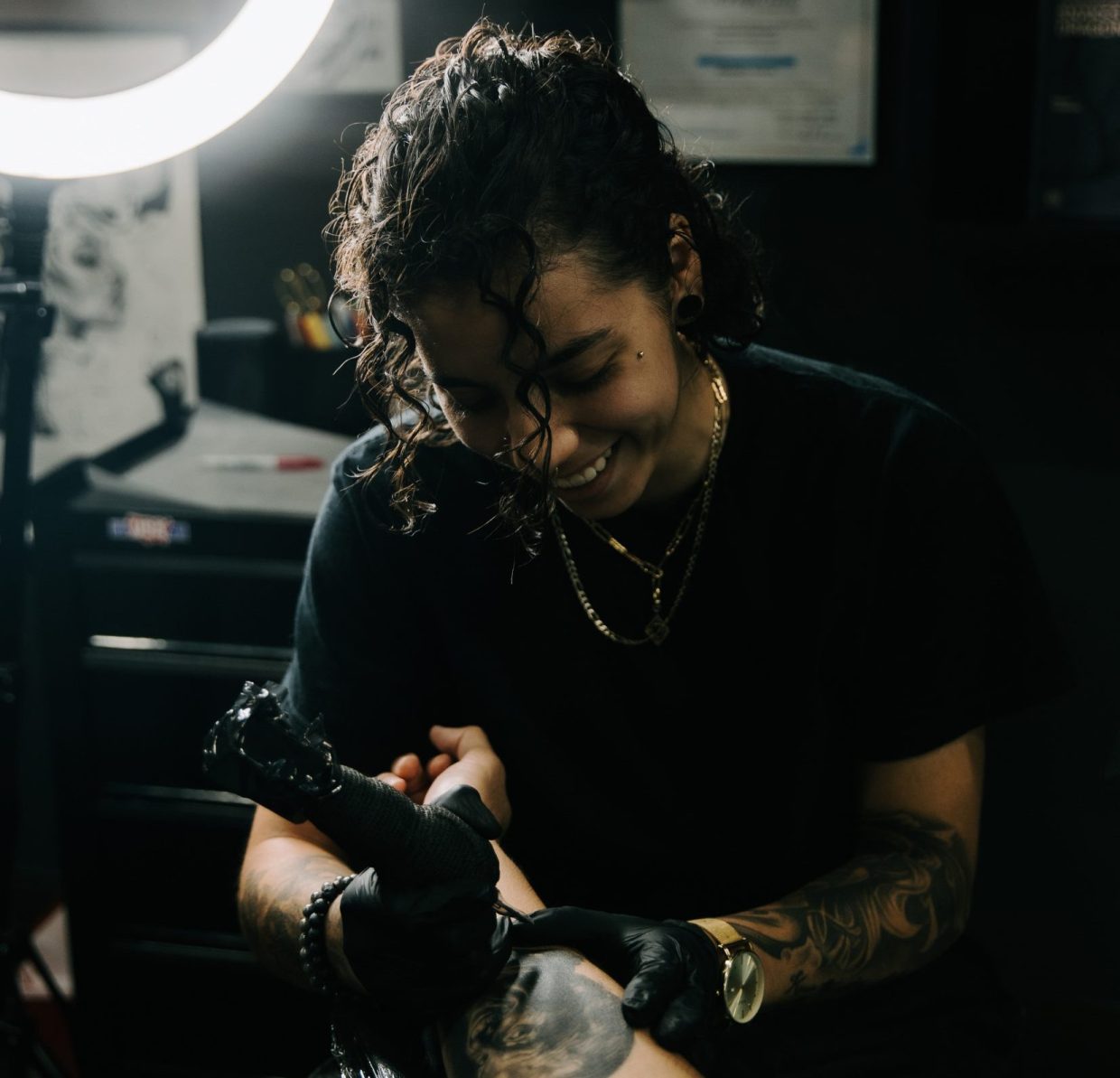 a woman works on a tattoo