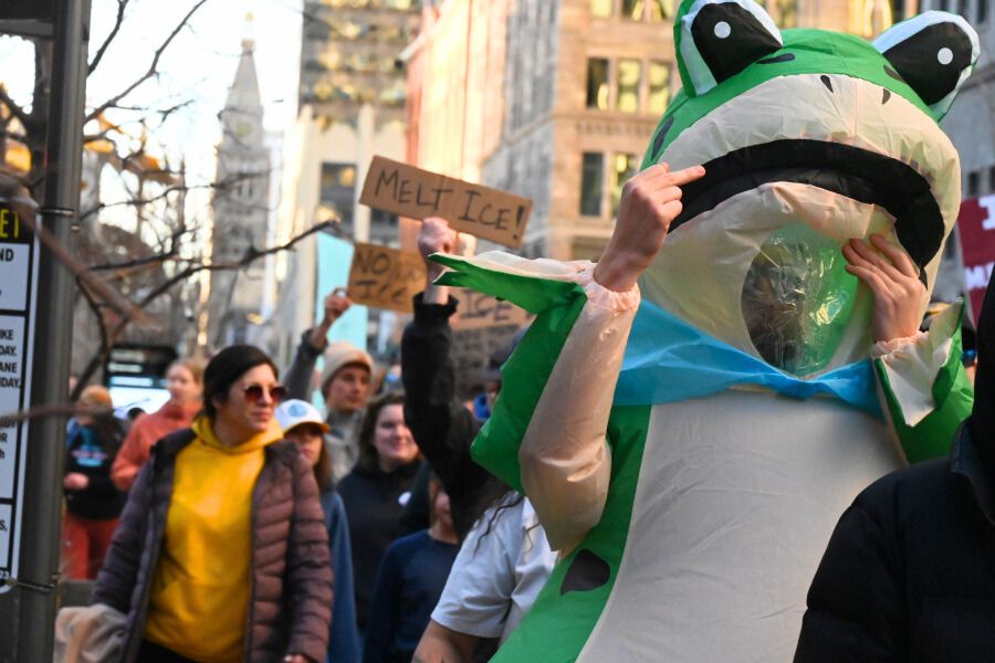 protesters march in downtown denver, including a man in an inflatable frog suit