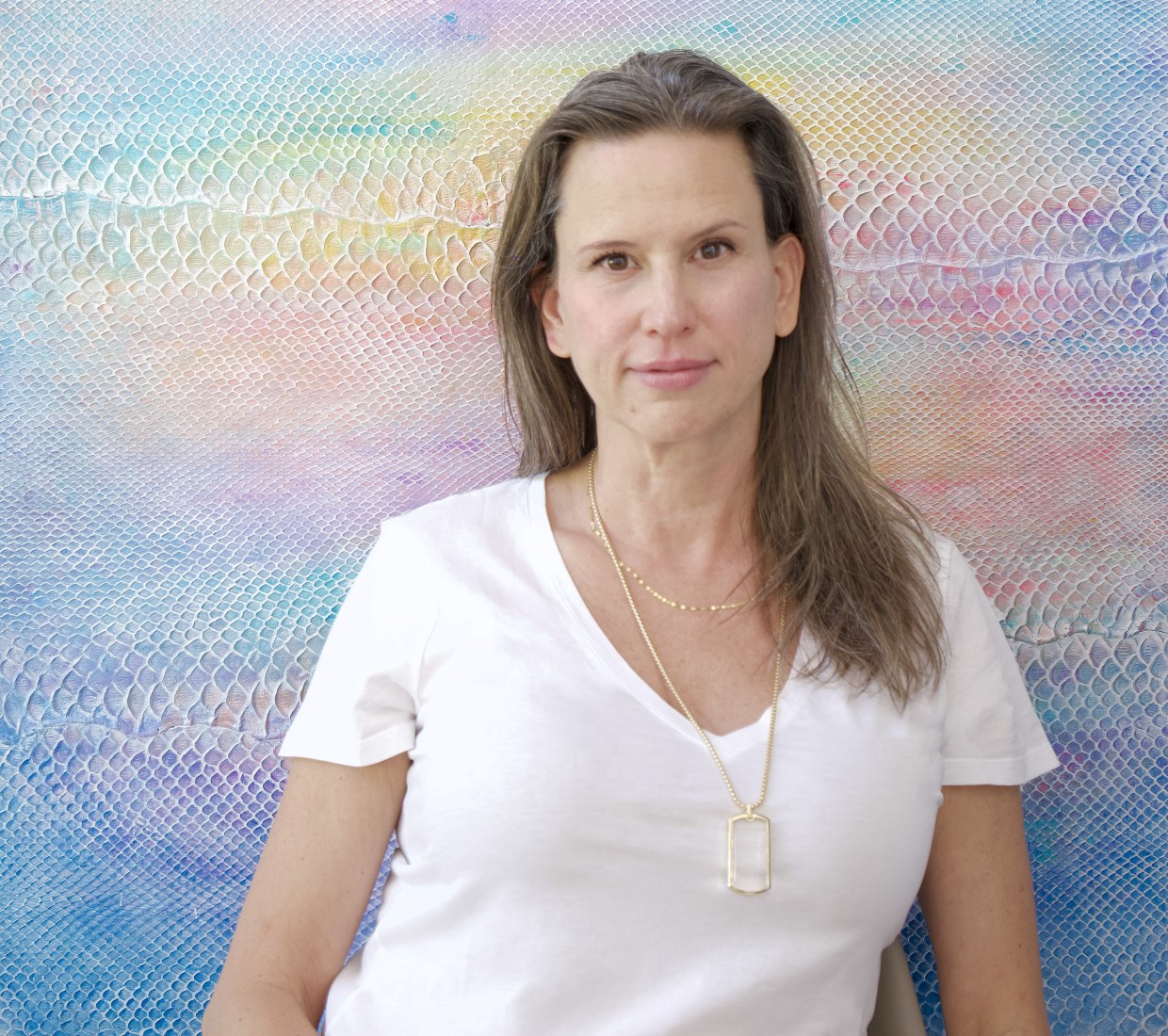 Artist Laura Shape stands in front of a colorful painting made of the skin of an invasive python species.