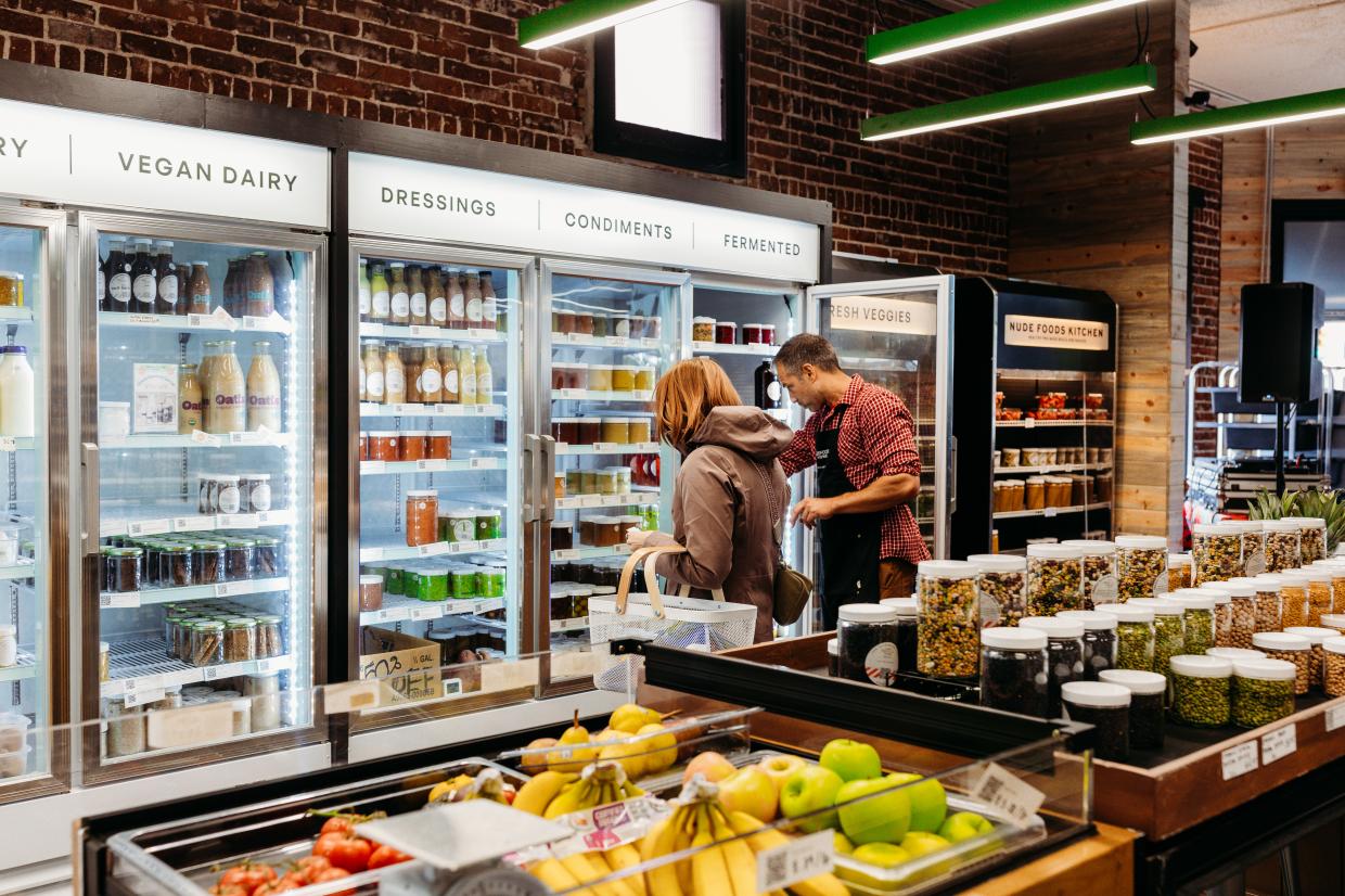 A customer and a staff member perusing the refrigerated goods at Nude Foods Market