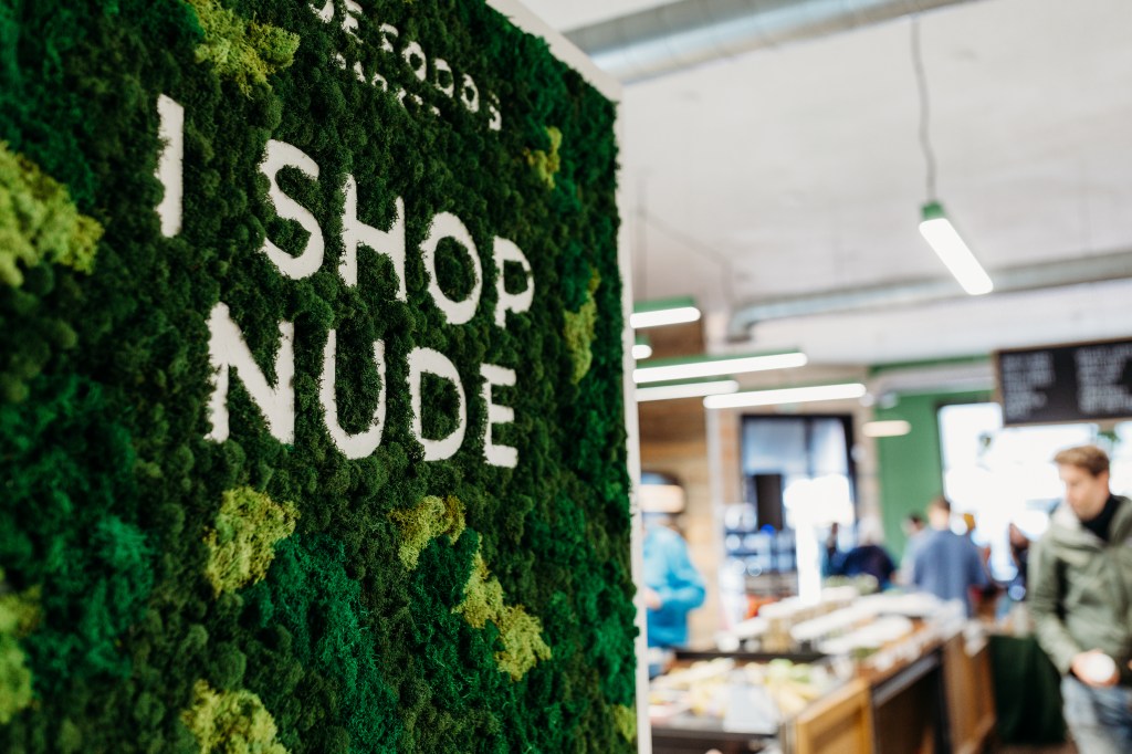 A moss wall art piece at the market reading "I shop Nude"