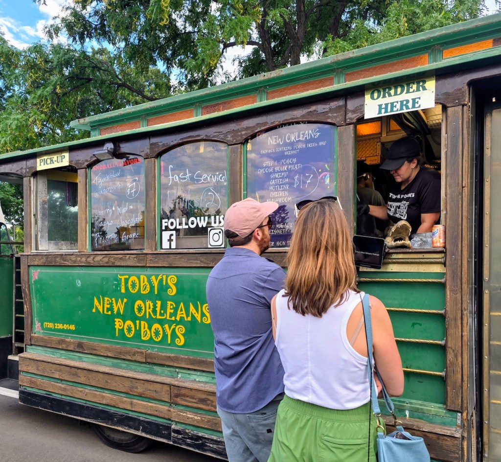 two people standing in front of a trolley food truck