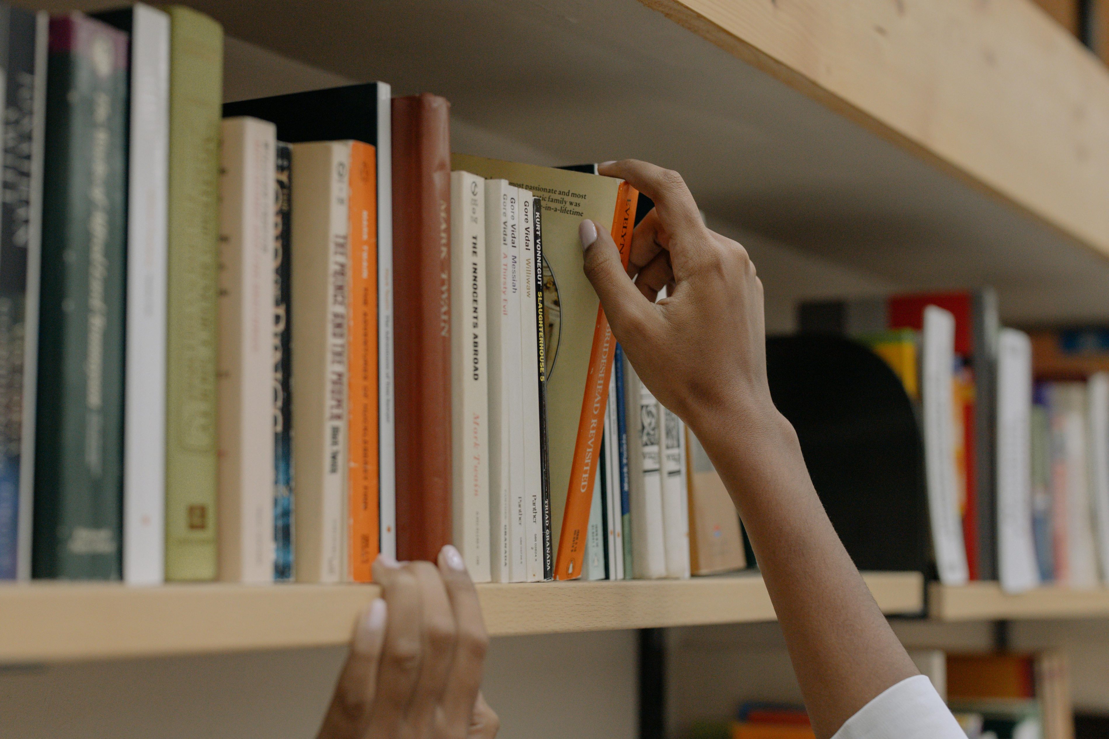 A person grabs a book from a shelf