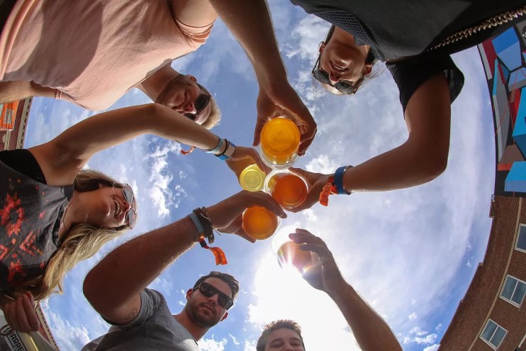 people cheers each other with drinks while standing outside