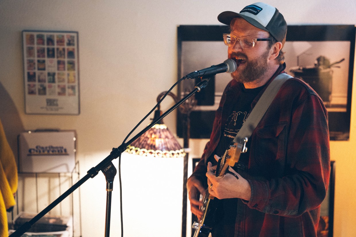 A person with a guitar singing into a microphone.