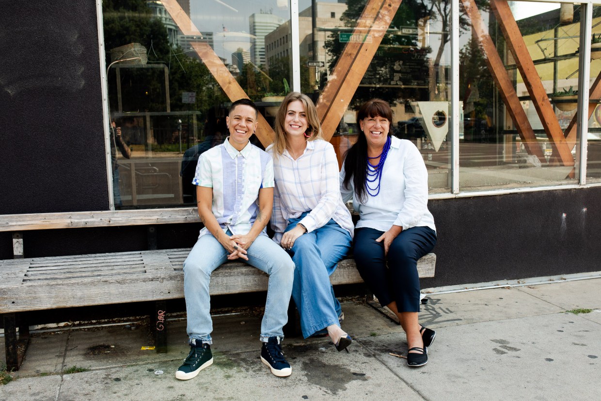 three people posing in front of a building