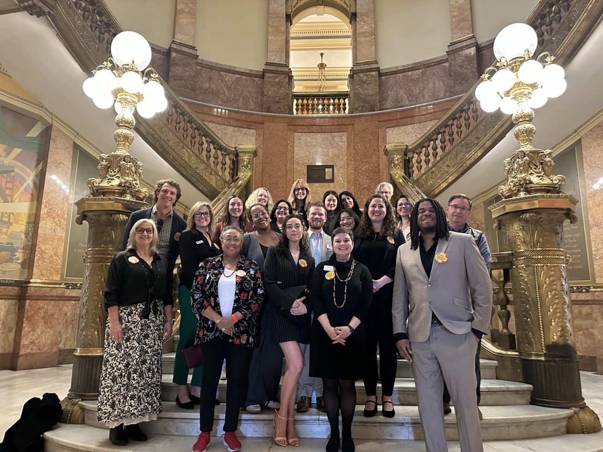 A group of people stand on the steps of the Capitol after March was made Arts Education Month.