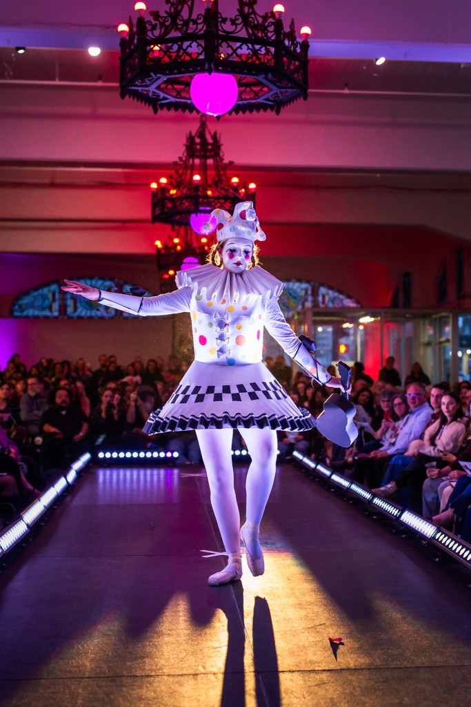 A person wears a clown costume made of paper for a paper fashion show