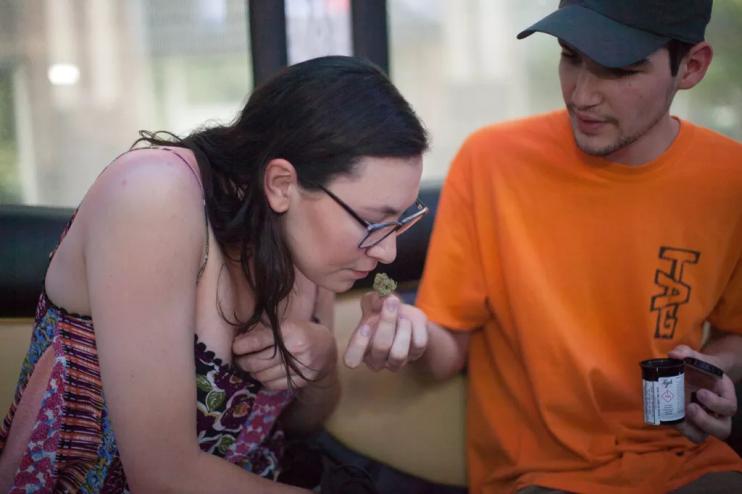 A woman smells a marijuana bud aboard a tour bus