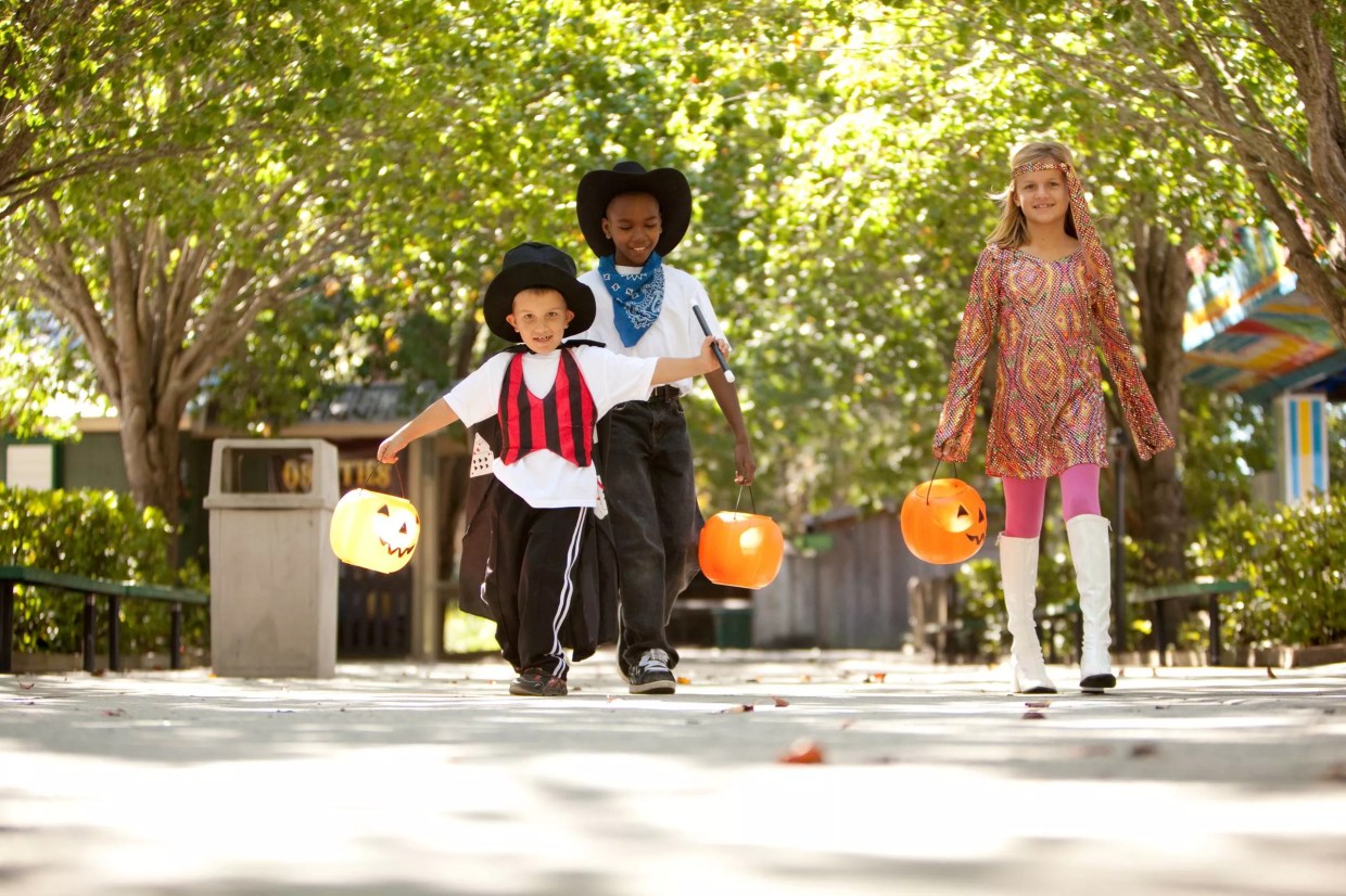 kids in Halloween costumes holding pumpkin containers for trick-or-treating