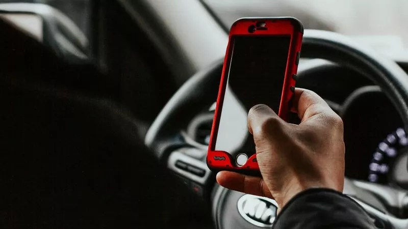 Person holds cellphone while driving